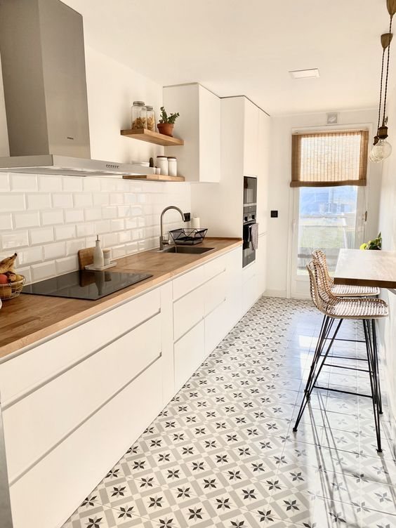 Cocina blanca lineal con encimera de madera y suelo hidráulico