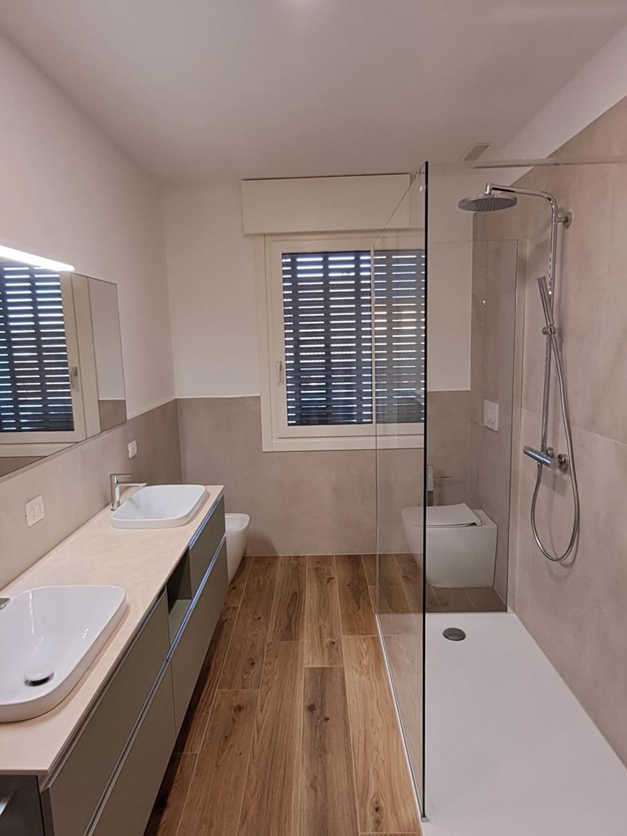 Baño alargado con doble lavabo y ducha
